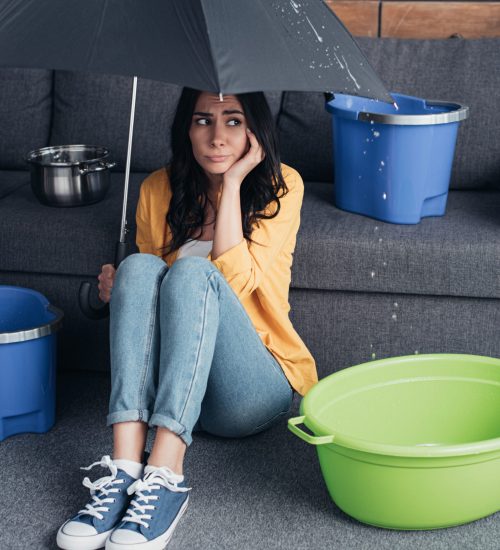 Sad girl in jeans sitting on floor with umbrella